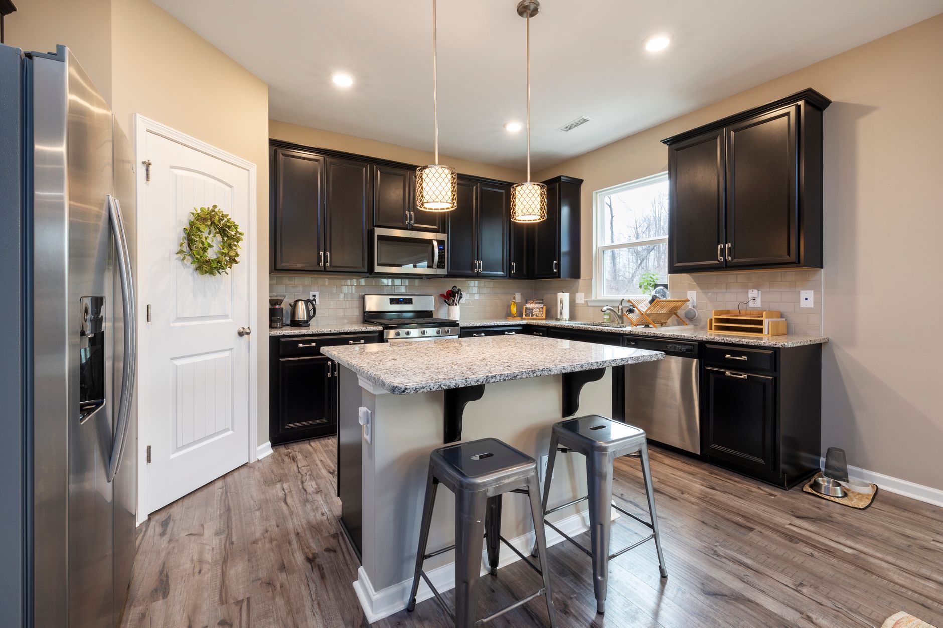 Sleek kitchen design featuring black cabinets, granite countertop island, and stainless steel appliances